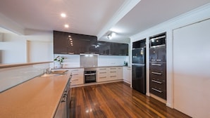 Una cucina moderna con pavimento in legno, mobili bianchi ed elettrodomestici in acciaio inossidabile.