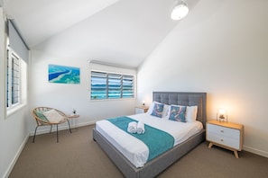 Une chambre à coucher avec un lit, une chaise, une table de chevet, un tableau et une fenêtre.