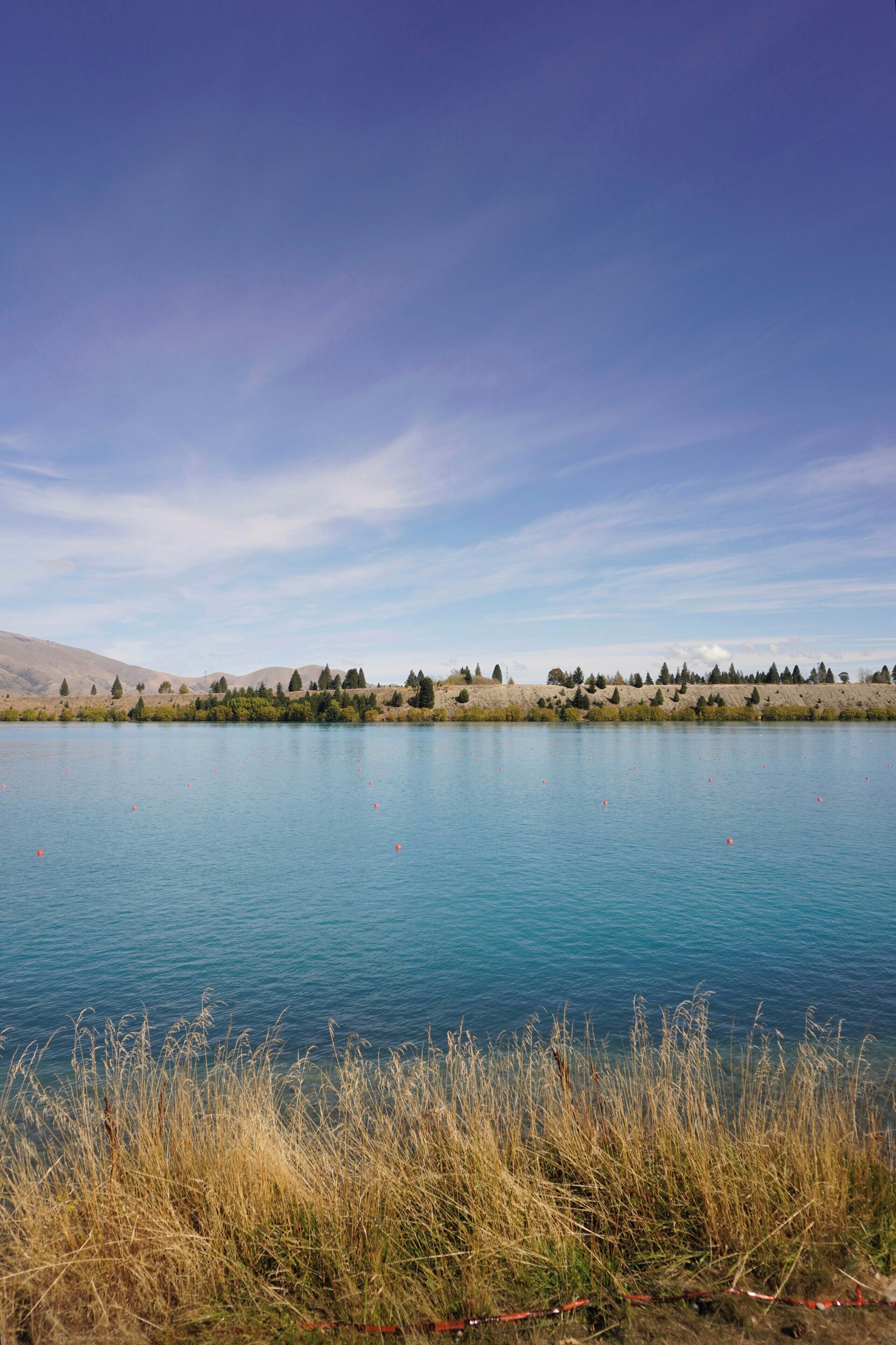 Un lac paisible, sous un ciel dégagé, avec des collines qui se dessinent à l'horizon.