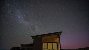A modern house with a large window and a car parked outside at night under a starry sky. - TWIZEL - House near the lake (Twizel)