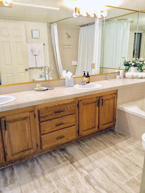 A modern bathroom with a wooden vanity, two sinks, a large mirror, and a shower area. - Dreamy Summer Stay-Cozy Condo for Couples (St George)