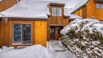A wooden cabin with a snow-covered roof and a wooden door.