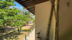 Un balcón con vista a un jardín, un cactus en maceta y un gancho de metal.
