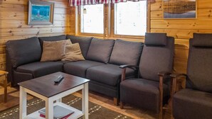 A cozy cabin interior with a wooden interior, a sofa, a table, and two chairs. - Lapinkulta a by Interhome (Äkäslompolo)