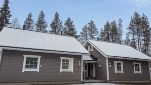 A two-story building with a grey exterior and white trim, featuring a covered entrance and a small porch. - Lapinkulta a by Interhome (Äkäslompolo)