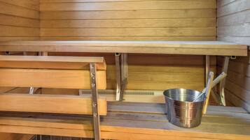 Un sauna avec des bancs en bois et un seau en métal.