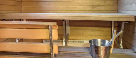 Eine Sauna mit Holzbänken und einem Metalleimer.
