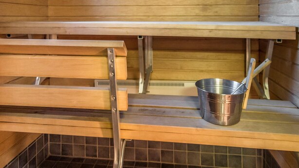 A sauna with wooden benches and a metal bucket. - Lapinkulta a by Interhome (Äkäslompolo)