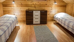 A cozy attic bedroom with two beds, a dresser, and a window with plaid curtains. - Lapinkulta a by Interhome (Äkäslompolo)