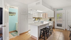 A kitchen with white cabinets, a central island with stools, a microwave, and a coffee maker. - ❃ Walkable to Food & Fun ❃ Beach-Front Pool ❃ Canal-Side Home ❃ No Pet Fee (Panama City Beach)