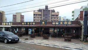A row of outdoor seating at a restaurant with a tiled roof and a signboard displaying the restaurant's name. - Triplex in Caiobá-Matinhos-Pr 200 m from the sea (Matinhos)