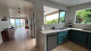 Cocina moderna equipada con lavavajillas, pileta y cafetera. Amplia ventana con vista a zonas verdes.