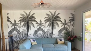 Una sala de estar moderna con un sofá azul claro, una mesa de centro de madera y un mural de palmeras en la pared.