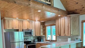 A kitchen with wooden cabinets, stainless steel appliances, and a wooden island with stools.