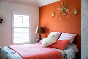 Quarto com cama, janela e detalhes decorativos nas paredes.