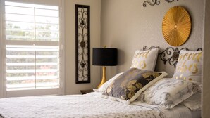 A neatly made bed with patterned bedding, a bedside lamp, decorative wall art, and a window with blinds. - ★ Luxurious Two-Story Home ★ Near La Cantera/Rim (San Antonio)