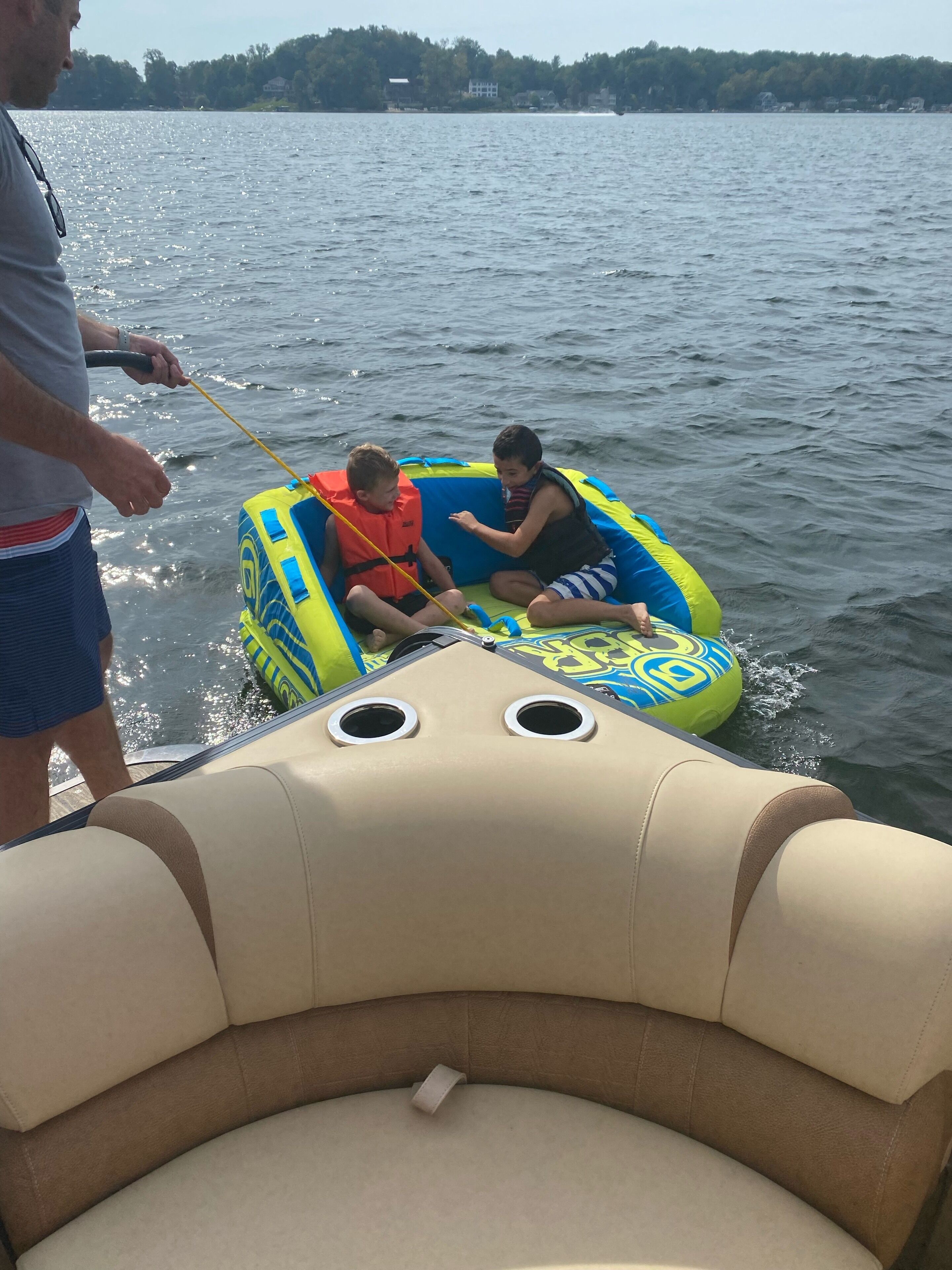 Un hombre de pie en un bote con dos niños en un bote inflable.
