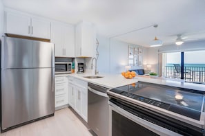 Una cucina moderna con elettrodomestici in acciaio inossidabile, mobili bianchi e vista all'esterno.