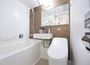 Uma casa de banho moderna com banheira, sanita, lavatório e espelho.