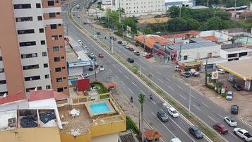 A multi-story building with a rooftop pool and a yellow structure with a red roof.