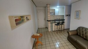 Een knus woongedeelte met een kitchenette, een bank en een kleine tafel.