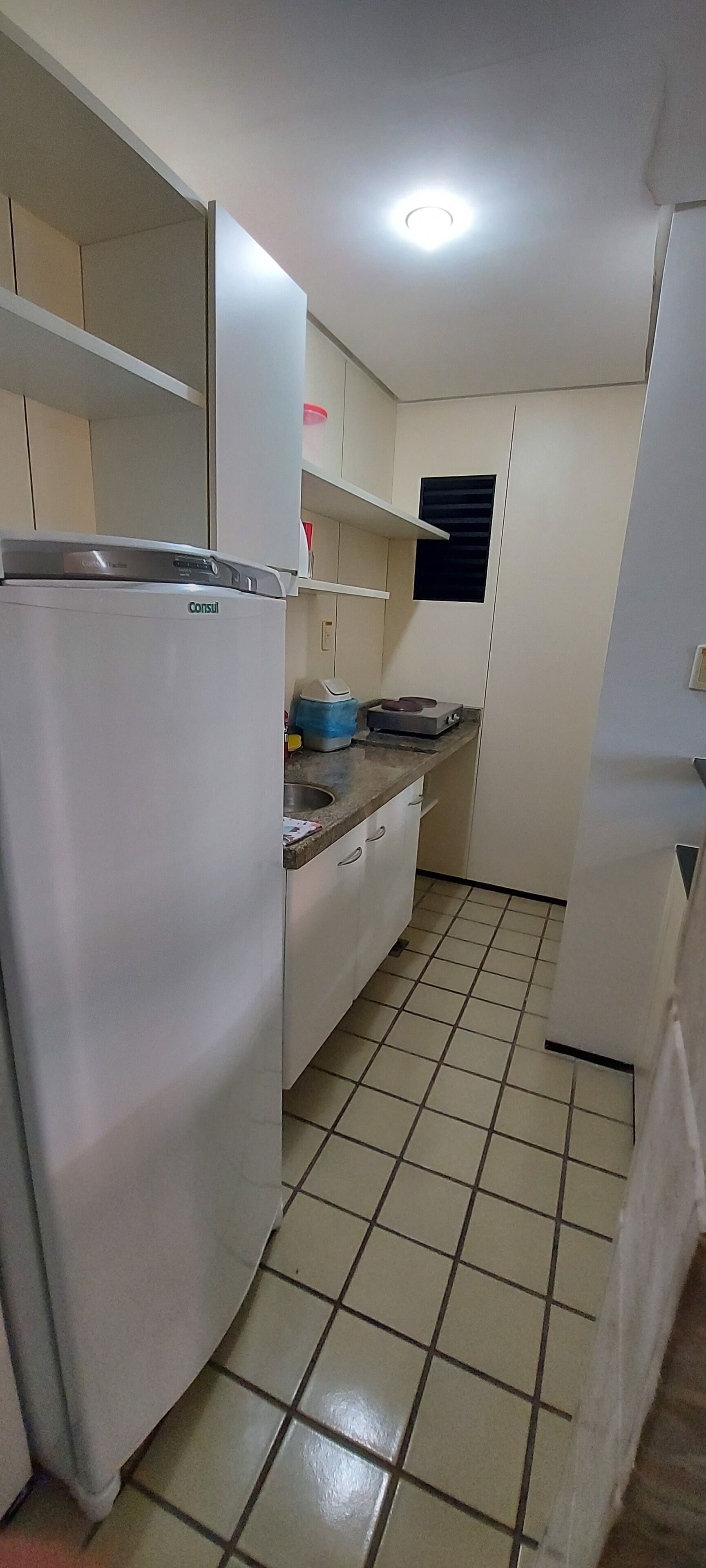 A compact kitchen with a refrigerator, a sink, and a countertop.