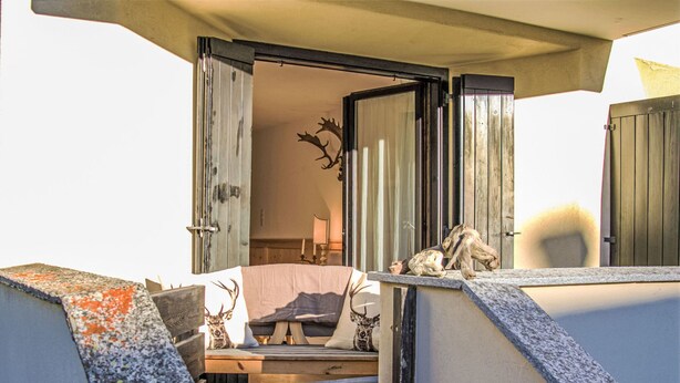 Una habitación acogedora con una cama, un banco de madera y una decoración de cabeza de ciervo.