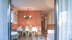 Una habitación acogedora con una mesa de comedor para cuatro, sillas de madera, un sofá blanco y una pequeña mesa de centro.