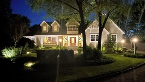 A two-story house with a front porch, a garage, and a well-maintained lawn. - Waterfront Villa near Hamptons with pool, hot tub & boat dock (Center Moriches)