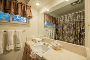 Un baño con lavamanos, espejo y toallero.