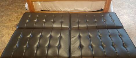 A bed with a wooden headboard, a colorful blanket, and a patterned pillow.
