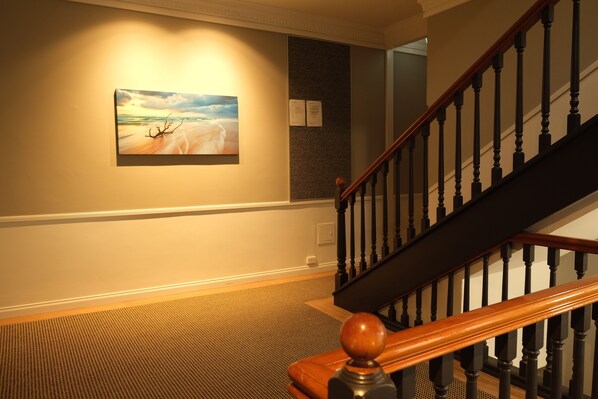 A staircase with wooden balusters and a handrail, carpeted floor, and a painting on the wall. - World famous beach location Manly (Sydney)