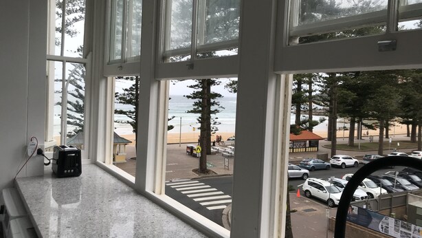 A room with large windows overlooking a beach and parking area. - World famous beach location Manly (Sydney)