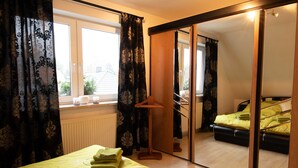 Habitación de hotel con cama, espejo y ventana con cortinas.