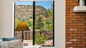 A room with a large sliding glass door leading to a patio with a view of a hilly landscape.
