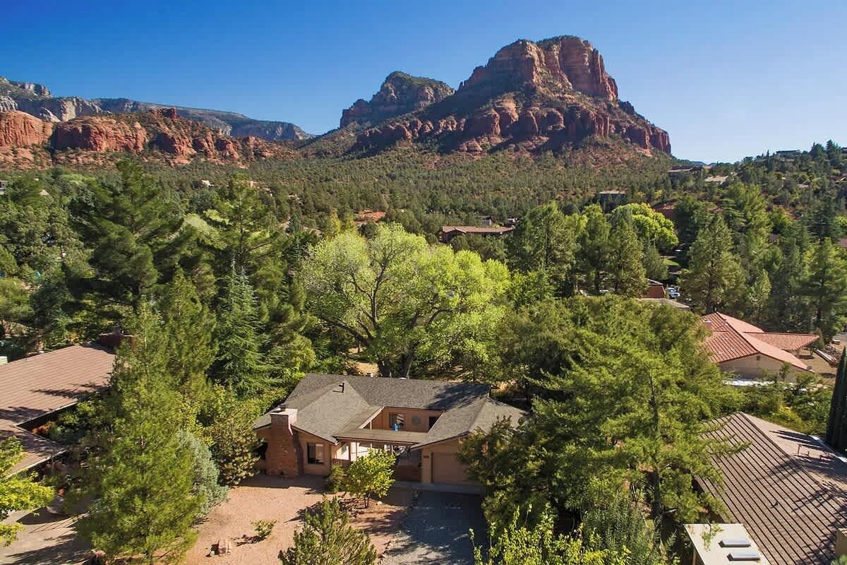 A residential area with houses surrounded by trees and a prominent mountain in the background.