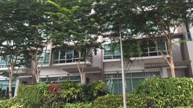 A multi-story building with a modern architectural design, surrounded by lush greenery and trees.