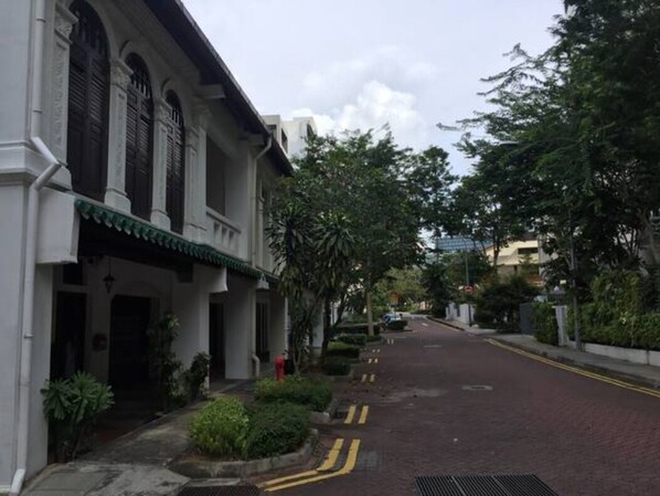 A street with traditional architecture, a paved road, and greenery. - Orchard Rd - Big Master Room (Singapore)