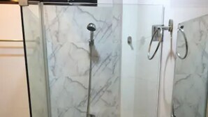 A bathroom with a glass-enclosed shower, a white sink, and a toilet.