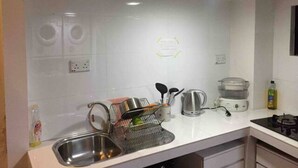 A modern kitchen with a stainless steel sink, a kettle, a coffee maker, and a dish rack.