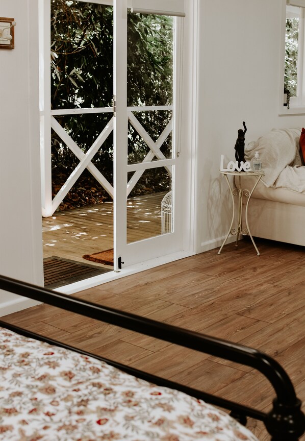 Una stanza con un letto, un tavolino con la scritta 'Love', un divano bianco e vista su un pontile in legno e sulla vegetazione circostante.