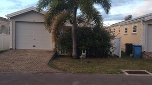 A residential garage with a brick driveway, a palm tree, and a mailbox.