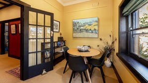A dining area with a round table, black chairs, a bookshelf, and a painting on the wall. - Cullalo ArtHouse- gorgeous accommodation combined with an art gallery! - Stunning one bedroom apartment in east Albury (East Albury)