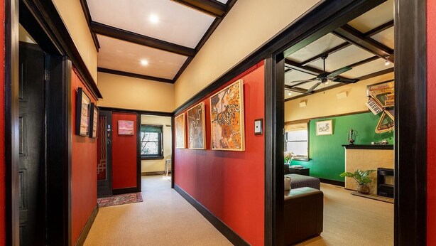 A hallway with red walls, a ceiling fan, and a green wall in the background. - Cullalo ArtHouse- gorgeous accommodation combined with an art gallery! - Stunning one bedroom apartment in east Albury (East Albury)