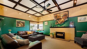 A living room with a fireplace, leather sofas, and a ceiling fan. - Cullalo ArtHouse- gorgeous accommodation combined with an art gallery! - Stunning one bedroom apartment in east Albury (East Albury)