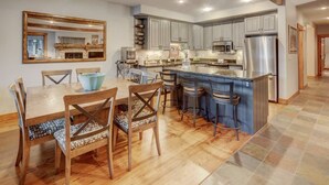 A spacious kitchen with a large island, wooden chairs, and a dining table.