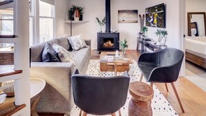 A modern living room with a fireplace, a sofa, two chairs, a coffee table, and a TV.
