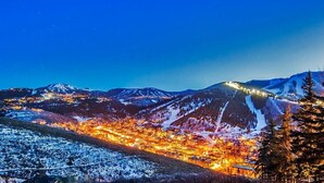 A mountainous landscape at night with illuminated buildings and snow-covered slopes.