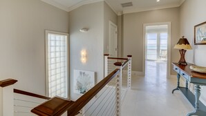 Un pasillo espacioso con una escalera de madera, vistas al exterior y una mesa con una lámpara.