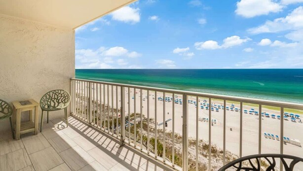 Un balcon donnant sur la plage, avec une balustrade et deux chaises.